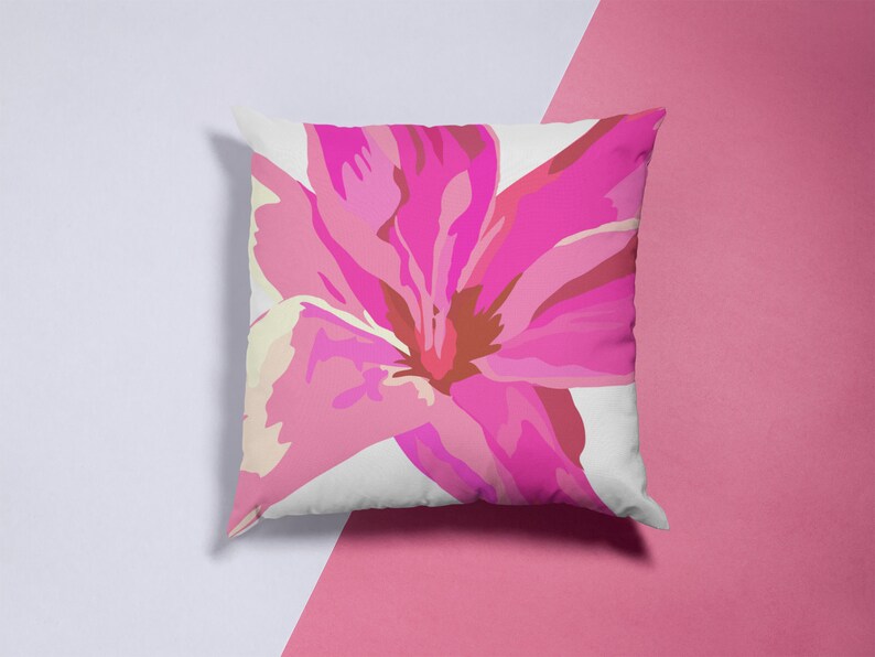 May include: A white pillow with a pink flower design. The flower has a pink and white center and petals.