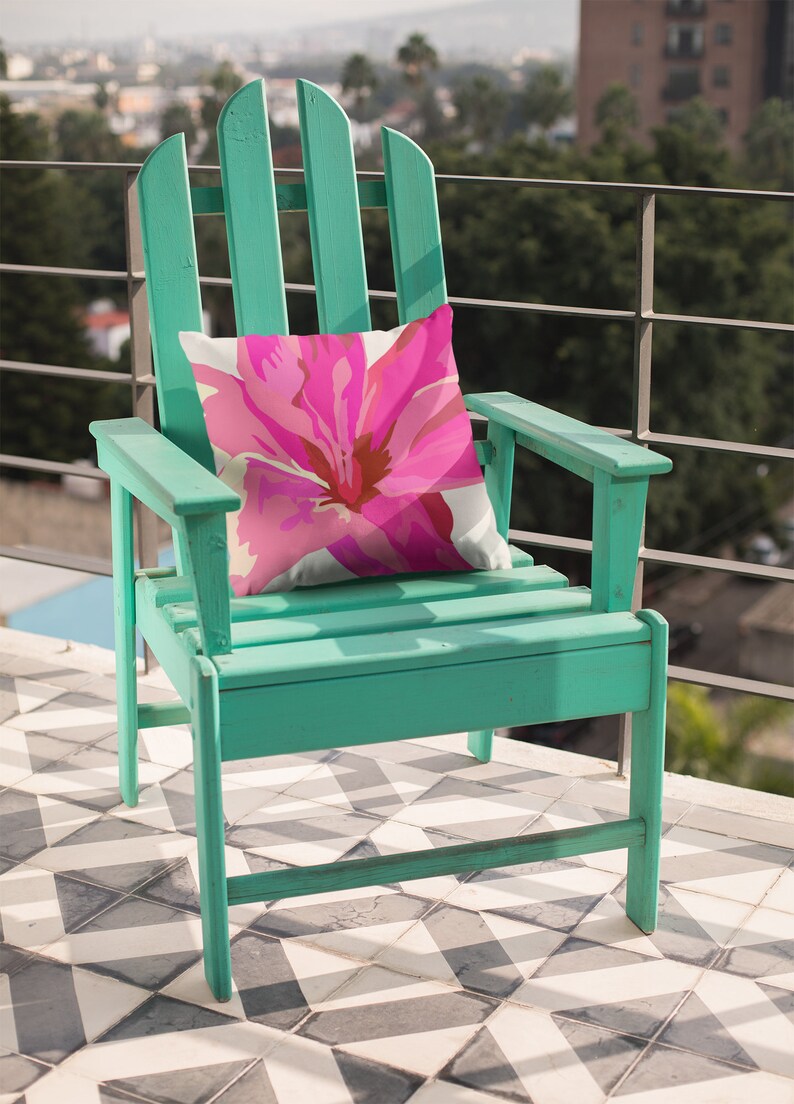 May include: A teal green wooden adirondack chair with a pink floral pillow. The chair is on a black and white tiled patio.