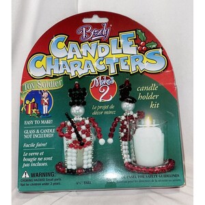 May include: A red and white beaded toy soldier candle holder kit. The kit includes beads, wire, and a glass candle holder. The package says "Beady Candle Characters Makes 2 Toy Soldier candle holder kit".