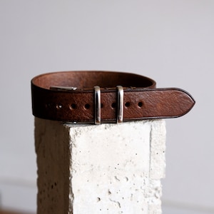 May include: A brown leather watch strap with silver buckle and keeper.