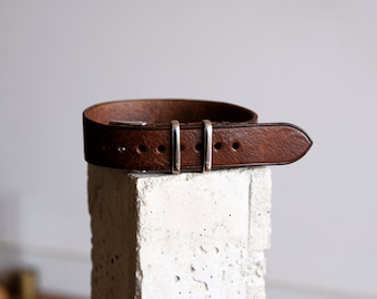 May include: A brown leather watch strap with silver buckle and keeper.