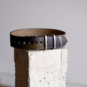 May include: A brown leather watch strap with a camouflage pattern and gold-tone hardware.