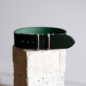 May include: A dark green leather watch strap with silver buckle and keeper.
