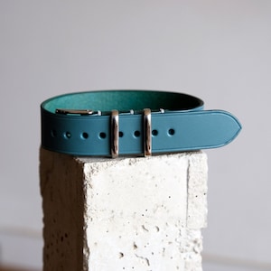 May include: A teal blue leather watch strap with silver buckle and keepers.