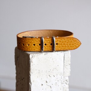 May include: A yellow leather watch strap with silver buckle and keepers.
