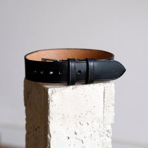 May include: A black leather watch strap with a silver buckle.