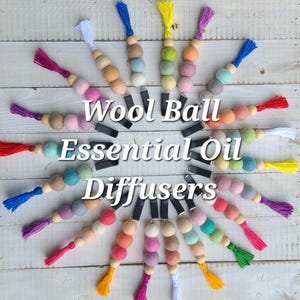 May include: A collection of colorful wool ball essential oil diffusers. Each diffuser features a string of felt balls in various pastel colors, a wooden bead, a tassel, and a black clip. The text "Wool Ball Essential Oil Diffusers" is displayed.