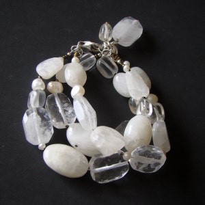 May include: A white crystal bracelet with clear and opaque beads. The bracelet is made of natural stones and has a silver clasp.