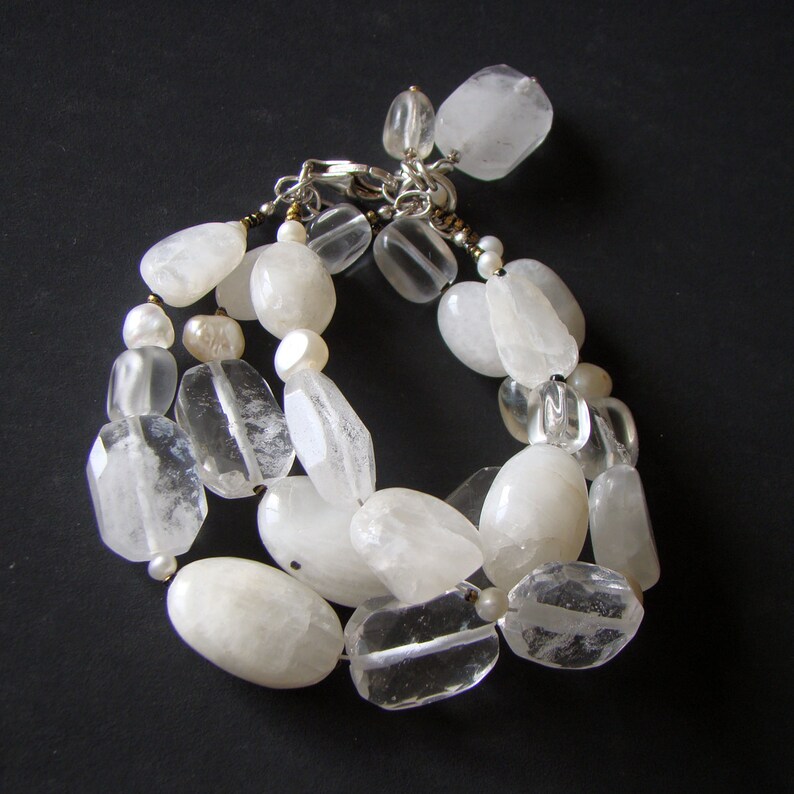 May include: A white crystal bracelet with clear and opaque beads. The bracelet is made of natural stones and has a silver clasp.
