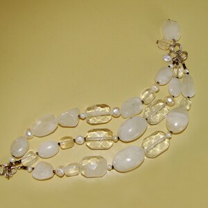 May include: A three-strand bracelet made of white and clear faceted stones. The bracelet has a silver clasp.