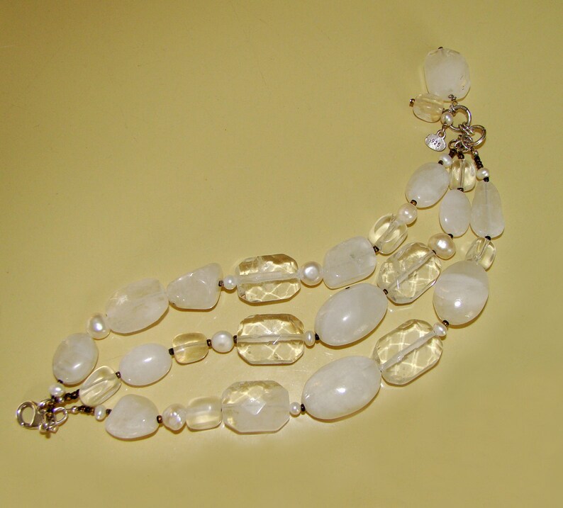 May include: A three-strand bracelet made of white and clear faceted stones. The bracelet has a silver clasp.