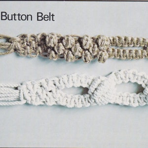 May include: Two different styles of macrame belts. The top belt is a brown button belt with a simple knot pattern. The bottom belt is a white berry belt with a more intricate knot pattern.