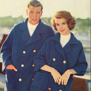 May include: Two people wearing blue double-breasted peacoats with gold buttons. The woman is wearing a white turtleneck sweater and the man is wearing a white turtleneck shirt.