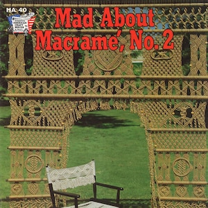 May include: A vintage macrame pattern book with the title "Mad About Macrame, No. 2". The cover features a macrame wall hanging with a chair and footstool in the foreground.