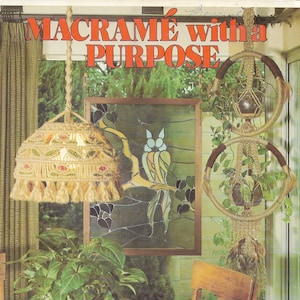 Puede incluir: Un libro titulado "Macramé con un propósito" con instrucciones para 15 proyectos de macramé. La portada presenta un macramé para colgar plantas, una pantalla de lámpara de macramé y una ventana de vitrales con un pájaro.
