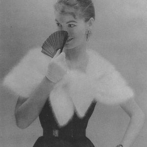 May include: A woman wearing a white fur shawl and a black dress with a black belt. She is holding a black and red folding fan in front of her face.