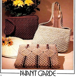 Pode incluir: Três bolsas de macramé em tamanhos e cores diferentes. A maior bolsa é bege com um padrão de diamante, a bolsa média é marrom com um padrão tecido e a menor bolsa é bege com detalhes marrons e um padrão geométrico. As bolsas são exibidas em uma superfície marrom claro com um buquê de flores amarelas no fundo. O texto "Avant Garde" é impresso abaixo das bolsas.