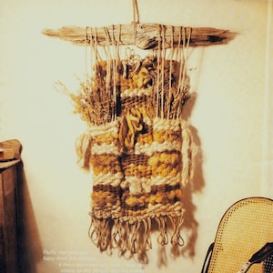 May include: A rustic wall hanging made with natural materials like jute and wool. The hanging features a woven design with earthy tones of brown and beige. The hanging is displayed on a wall with a wooden chair and a musical instrument.