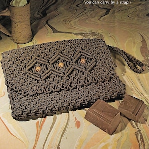 May include: A brown crocheted clutch purse with wooden beads and a strap. The purse is sitting on a marbled surface with two pieces of dark chocolate next to it. The text "HOT CHOCOLATE" is written in large letters above the purse. The text below the purse reads "Daytime or evening - like a cup of hot chocolate, this purse is a pleasure anytime. (Extra pleasure: a clutch you can carry by a strap.)"