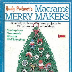 May include: A book cover with the title "Judy Palmer's Macrame Merry Makers" and a green macrame Christmas tree with decorations. The book cover is blue with a white border and the text is in red and white.