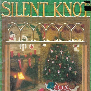 May include: A vintage book cover with the title "Silent Knot" in gold lettering on a green background. The cover features a window scene with a fireplace, a decorated Christmas tree, and a child sleeping on the floor. The text below the window reads "Classic presents an Old Fashioned Christmas - Come On Inside and Join Us..."