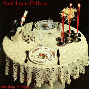 May include: A vintage knitting pattern for a candlelit dinner tablecloth. The pattern features a delicate lace design with a floral motif. The image shows a table set with a white tablecloth, candles, and a bottle of champagne.