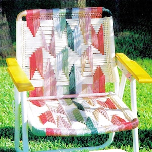 Può includere: Una sedia pieghevole bianca con un bracciolo in legno giallo e una seduta e uno schienale intrecciati colorati. La seduta e lo schienale sono intrecciati con corda rosa, verde e bianca.