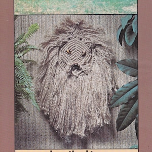 May include: A brown and white yarn lion head wall hanging with the text "Leo the Lion" at the bottom. The lion has a brown nose and yellow eyes.