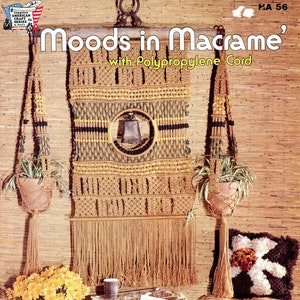 May include: A macrame wall hanging with a bell in the center, two macrame plant hangers, a macrame footstool, a macrame table, and a potted plant with yellow flowers. The wall hanging is made with brown, yellow, and green cord. The text "Moods in Macrame' with Polypropylene Cord" is printed at the top of the image.