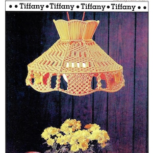 May include: A yellow macrame lampshade with a woven pattern hangs from the ceiling. The lampshade is over a table with a potted plant and a pitcher.