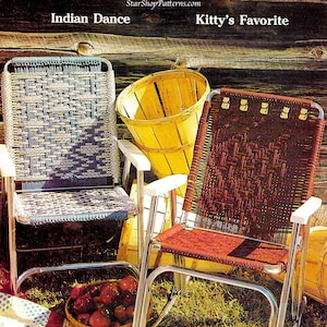 May include: Two woven chairs with metal frames, one in blue and white and the other in red and white, are sitting on a grassy surface. The chairs are labeled "Indian Dance" and "Kitty's Favorite". A basket of red apples sits in front of the chairs.