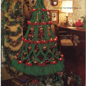 May include: A handmade green macrame Christmas tree adorned with red bows and gold baubles. The tree is illuminated with small lights and rests on a green fringe base. The text "Christmas Tree Delight - Page 14" is visible.