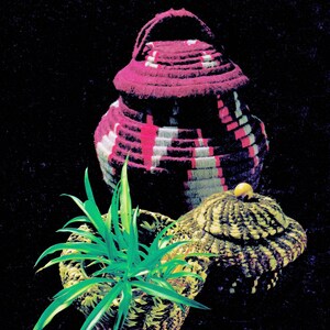 May include: Three woven baskets, one with a pink and white striped pattern, one with a brown and white striped pattern, and one with a green plant inside.