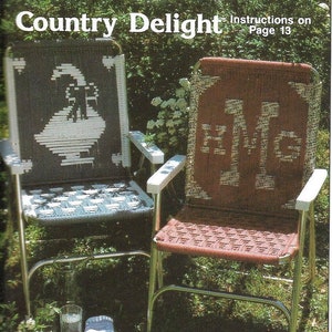 Könnte beinhalten: Zwei geflochtene Stühle mit Metallrahmen. Der Stuhl links hat ein weißes Vogelmotiv auf blauem Hintergrund. Der Stuhl rechts hat einen roten Hintergrund mit den Buchstaben "HMG" in Weiß. Die Stühle stehen in einem grasbewachsenen Bereich mit grünem Laub.