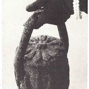 May include: A black beaded handbag with a round shape and a handle. The handbag is being held by a gloved hand.
