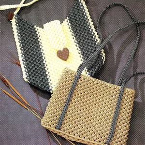 Puede incluir: Dos bolsos de crochet, uno con rayas blancas y negras y un botón en forma de corazón, y el otro con un diseño de rayas marrones y negras. El texto "Hearts and Stripes" y "Fashion Satchel" es visible en la imagen.