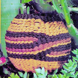 May include: A round woven wall hanging with a brown, purple and gold striped pattern. The hanging is made of thick rope and has a textured surface.