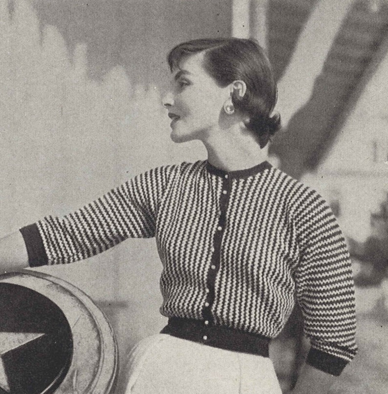 May include: A black and white striped cardigan with a button closure. The cardigan has a crew neckline and three-quarter sleeves.