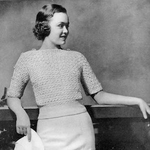 May include: A white crocheted sweater with a boat neck and short sleeves. The sweater features a delicate openwork pattern.