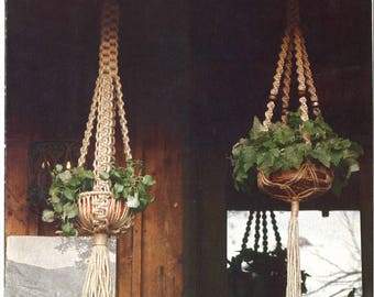 May include: Two macrame plant hangers with a natural rope design. The hangers are hanging from a wooden structure with a snowy roof. The hangers are holding green plants in brown pots. The text "Interessante Page 22" is on the left and "Au Naturel Page 22" is on the right.