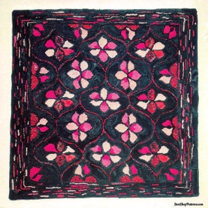 K&ouml;nnte beinhalten: Quadratischer Teppich mit dunkelblaugr&uuml;nem Hintergrund und einem sich wiederholenden Blumenmuster in Rosa- und Rott&ouml;nen. Die Blumen sind in einem Raster angeordnet, mit einem dekorativen Rand. Der Teppich ist wahrscheinlich handgefertigt.