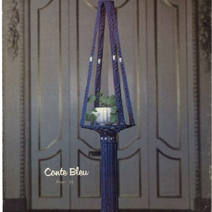 Peut inclure: Un porte-plante en macram&eacute; bleu avec un pot blanc et une plante &agrave; l'int&eacute;rieur. Le porte-plante est suspendu &agrave; un crochet sur une porte blanche. Le texte "Conte Bleu Page 13" est imprim&eacute; sous le porte-plante.