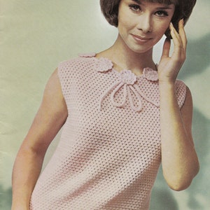 May include: A pink crocheted sleeveless top with a crocheted flower detail at the neckline.