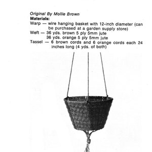 May include: A hanging garden basket made of brown and orange jute with a 12-inch diameter. The basket is suspended by two cords and has a tassel made of brown and orange cords.