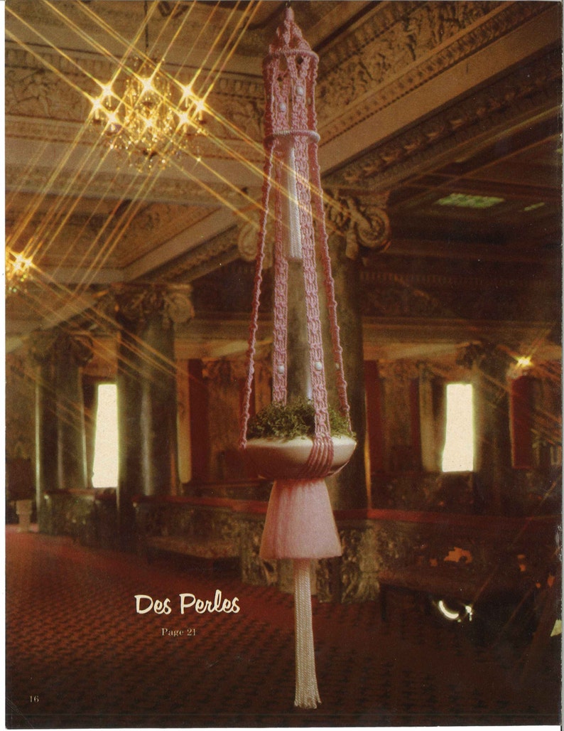 Peut inclure: Un porte-plante en macram&eacute; rose avec un pompon blanc suspendu au bas. Le porte-plante est dans une grande pi&egrave;ce orn&eacute;e avec un lustre.