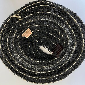May include: A rolled-up black hair net with white accents and a brown comb. The net has a tag that reads "John Frederics Made in America". The hair accessory is circular and appears to be vintage.