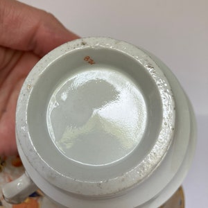 May include: The bottom of a white porcelain teacup with a brown number "128" printed on the bottom.