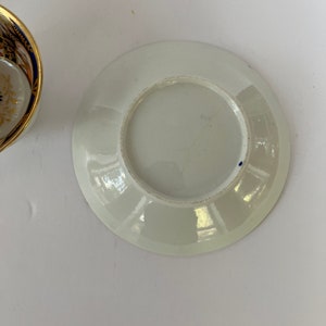 May include: White porcelain saucer with a blue rim and a slightly raised center.