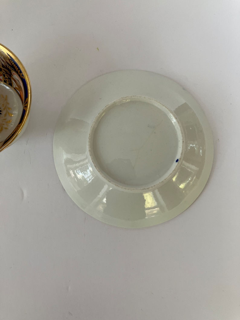 May include: White porcelain saucer with a blue rim and a slightly raised center.