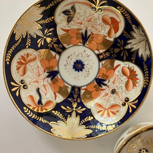 May include: A vintage porcelain teacup and saucer with a blue and white floral pattern. The saucer has a gold rim and intricate details. The teacup has a floral design in the center.